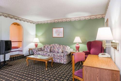 a living room with a couch and a tv at Super 8 by Wyndham Coshocton Roscoe Village in Coshocton