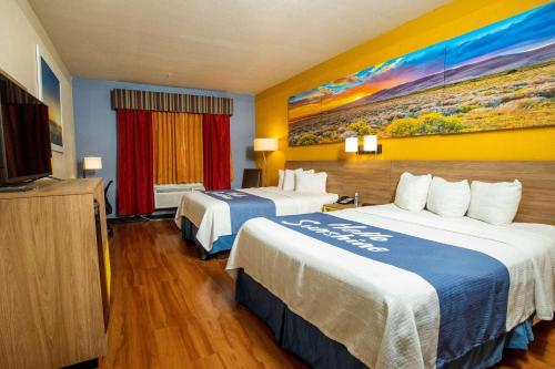 a hotel room with two beds and a flat screen tv at Days Inn & Suites by Wyndham Houston North/Aldine in Houston