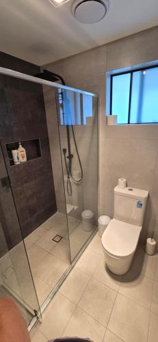 a bathroom with a toilet and a glass shower at New 5x bedroom The Ponds House in Schofields