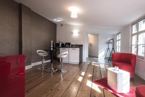un salon avec une chaise rouge et une table dans l'établissement Appartements Orfèvres Cathédrale, à Strasbourg