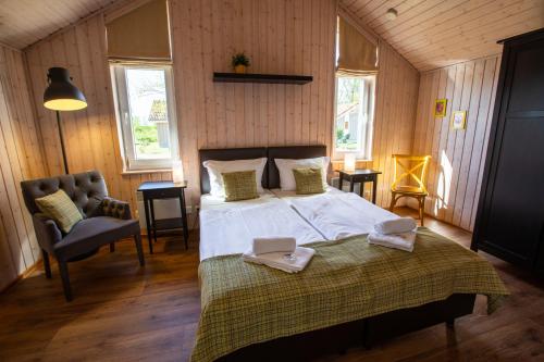 a bedroom with a bed and a chair and windows at Typ H "Lord Nelson" -Sundhaus- in Pelzerhaken