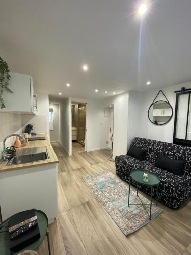 un salon avec un canapé noir et une cuisine dans l'établissement T2 en plein cœur du centre ville Coup de cœur garanti, à Marseille