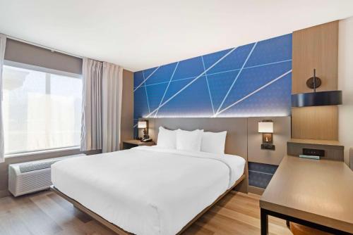 a bedroom with a large white bed and a blue wall at Comfort Suites Northside Hospital Gwinnett in Lawrenceville