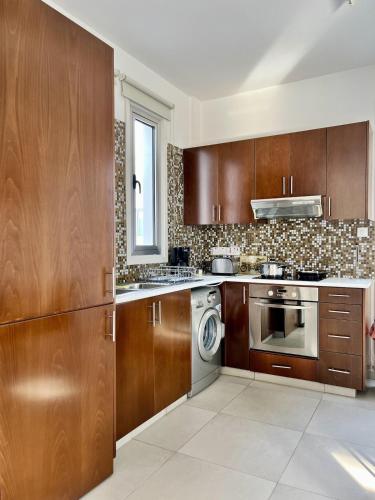 a kitchen with wooden cabinets and a washer and dryer at Luxury Villa Azure in Larnaca