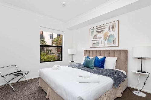 a white bedroom with a large bed with blue pillows at Renovated Townhouse in Northbridge in Perth