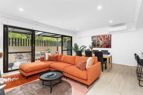 a living room with an orange couch and a table at Renovated Townhouse in Northbridge in Perth