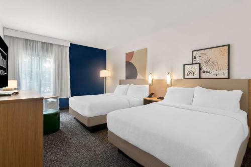 a hotel room with two beds and a television at Spark By Hilton Missouri City in Missouri City