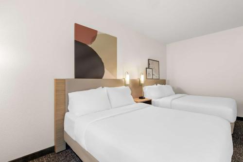 two beds in a hotel room with white walls at Spark By Hilton Missouri City in Missouri City