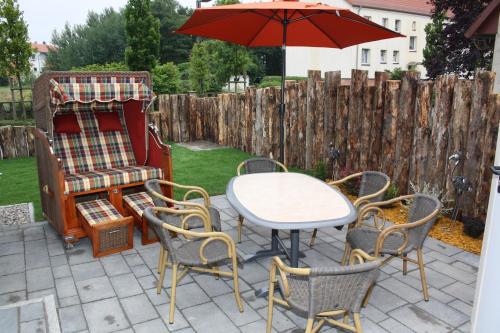 a patio with a table and chairs and an umbrella at FeHa Strandmügge in Zingst