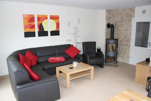 a living room with a black couch and red pillows at FeHa Strandmügge in Zingst