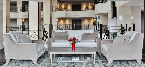 a lobby with two white couches and a table with flowers at Grand Mogador City Center in Casablanca
