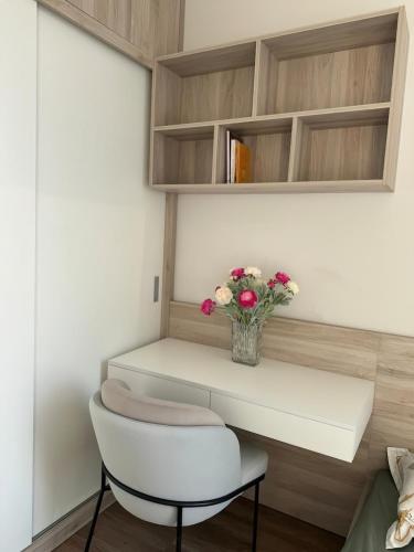 a white table with a vase of flowers and a chair at Landmark Ecopark by Emily in Town in Kim Quan