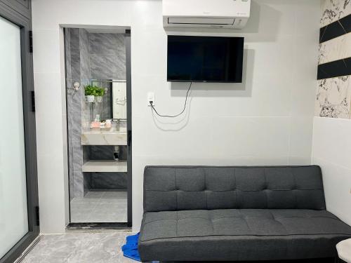 Lê Lộc Guesthouse في موي ني: غرفة معيشة مع أريكة وتلفزيون على الحائط