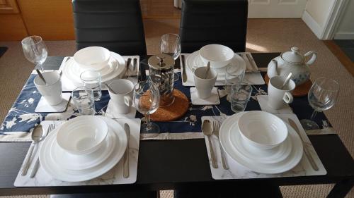a table with white plates and wine glasses on it at Ipswich Town 3 Bed House in Copdock