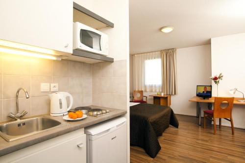 a kitchen with a stove, microwave, sink, and dishwasher at Séjours & Affaires Toulouse de Brienne in Toulouse