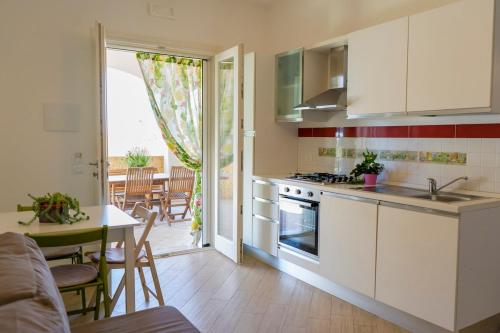 cocina con armarios blancos, mesa y comedor en Appartamento Villa Nisapiro' Sannicola, en Sannicola