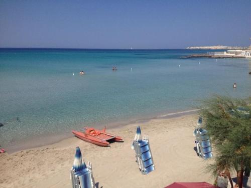 una playa con sillas y un barco en el agua en Appartamento Villa Nisapiro' Sannicola, en Sannicola