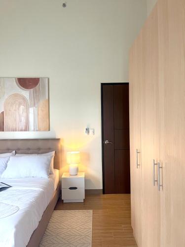 a bedroom with a white bed and a wooden cabinet at Opulent Spacious 3 BR Condominium at St Dominique at Megaworld in Iloilo City