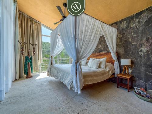 a bedroom with a canopy bed and a window at Luxury Oceanfront Villa - Private Pool -Temazacal in Chamela