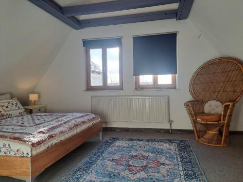 a bedroom with a bed and a chair and two windows at Zentrale Altbau Fewo Marktplatz in Gunzenhausen
