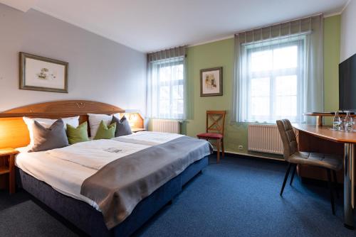 a hotel room with a bed and a desk and windows at Hotel Anna Amalia in Weimar