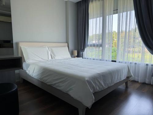 ein Schlafzimmer mit einem großen Bett und einem großen Fenster in der Unterkunft 6th Avenue Surin in Ban Lum Fuang