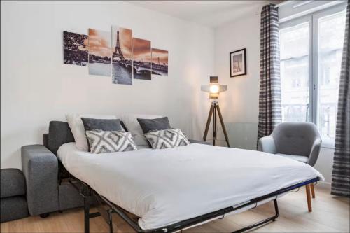 a white bedroom with a bed and a couch at Casaminnie - Appartement à 8 min de Disneyland Paris in Bussy-Saint-Georges
