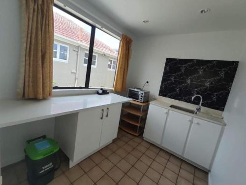a kitchen with white cabinets and a sink and a window at 6 Beds including 4 Double Beds and 2 Single Sofa Beds Serviced Chalet B in Auckland