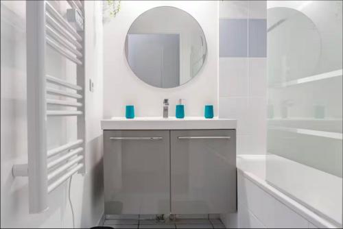une salle de bain blanche avec un lavabo et un miroir dans l'établissement Casaminnie - Appartement à 8 min de Disneyland Paris, à Bussy-Saint-Georges