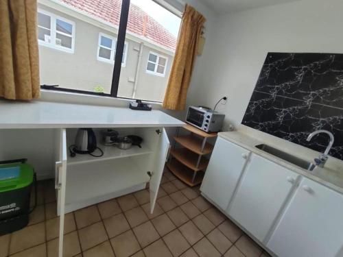 a kitchen with a counter and a sink and a window at 6 Beds including 4 Double Beds and 2 Single Sofa Beds Serviced Chalet B in Auckland
