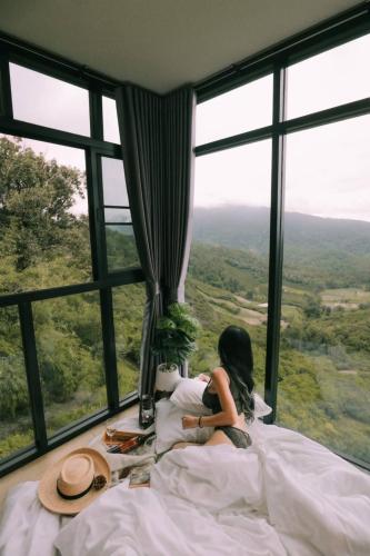 a girl sitting in bed in front of a window at ภูสิริ โฮมสเตย์ in Ban Thung Phan Ha