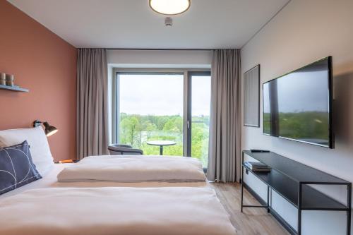 a hotel room with a bed and a large window at The Base Munich in Munich