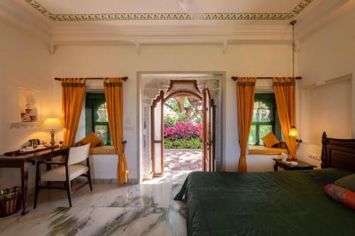 a bedroom with a bed and a desk and a door at Sardargarh Heritage Fort Udaipur in Sardārgarh