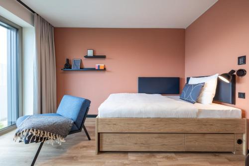 a bedroom with a bed and a chair at The Base Munich in Munich