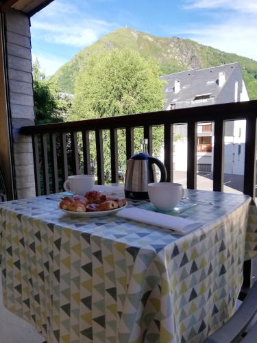 - une table avec une bouilloire et une assiette de nourriture sur un balcon dans l'établissement Appartement avec balcon au centre de Saint-Lary, à Saint-Lary-Soulan