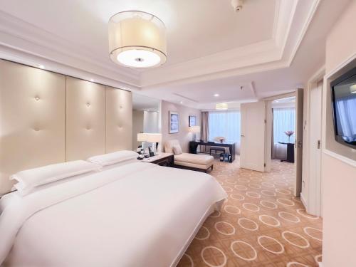 a bedroom with a large white bed and a living room at Sheraton Xi'an Hotel in Xi'an