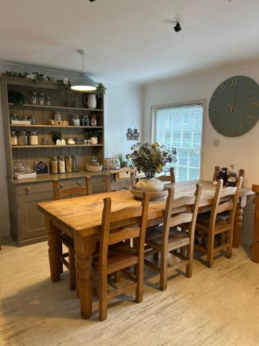 a dining room with a wooden table and a clock at Angel Cottage in stunning Arundel in Arundel
