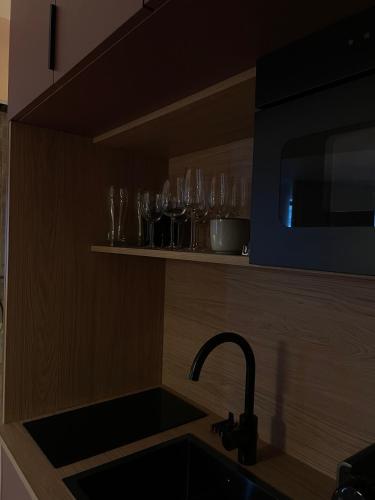 une cuisine avec évier et verres sur une étagère dans l'établissement Love Room Strasbourg, Sauna, Spa, Suite Ibiza, Évasion Romantique et Sensuelle, à Strasbourg