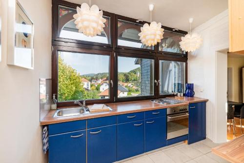 a kitchen with blue cabinets and a large window at Ferienhaus Villa Bourguet in Bad Liebenstein
