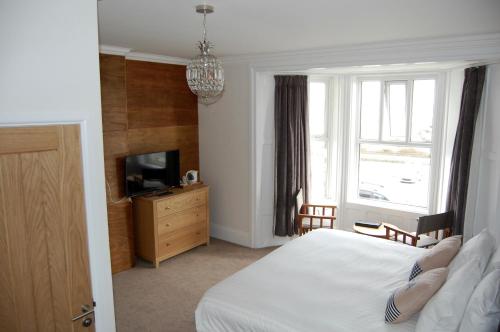um quarto com uma cama, uma televisão e uma janela em The Grosvenor Guest House em Bude