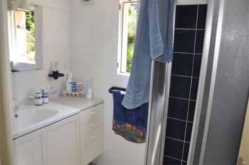 La salle de bains est pourvue d'un lavabo et d'une douche avec une serviette bleue. dans l'établissement Maison VUE MER de plain-pied avec WIFI à PLEUMEUR - BODOU REF-649, à Pleumeur-Bodou