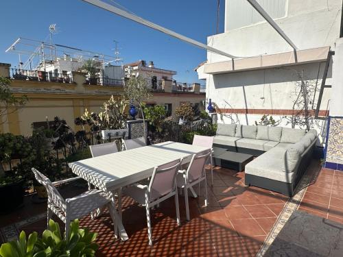 eine Terrasse mit einem Tisch, Stühlen und einem Sofa in der Unterkunft La Alcazaba de Triana in Sevilla