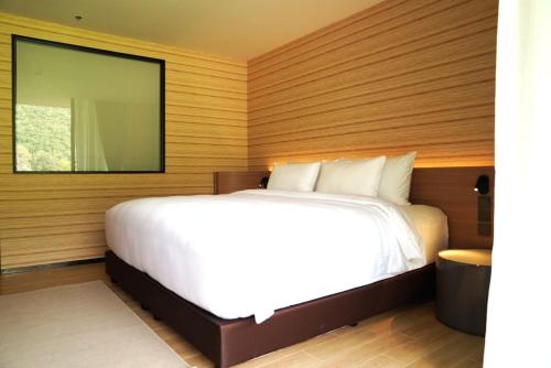 a bedroom with a white bed and a large mirror at Viewpoint Khaoyai Hotel in Mu Si