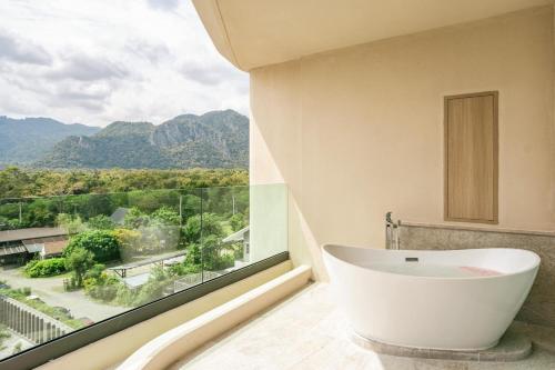 a bathroom with a tub and a large window at Viewpoint Khaoyai Hotel in Mu Si