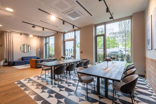 a meeting room with tables and chairs and windows at The Base Munich in Munich