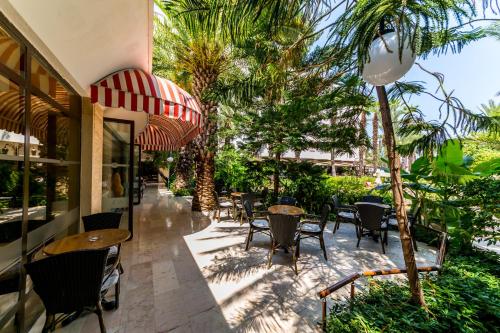 a patio with tables and chairs and palm trees at Hotel Aqua in Marmaris