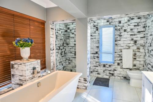 bagno con vasca e parete in pietra di Kings Beach Guest House a Port Elizabeth