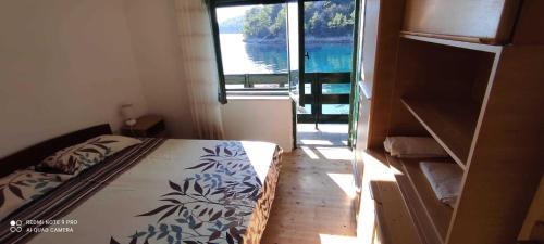 a bedroom with a bed with a view of the water at Robinson Mili in Bogomolje