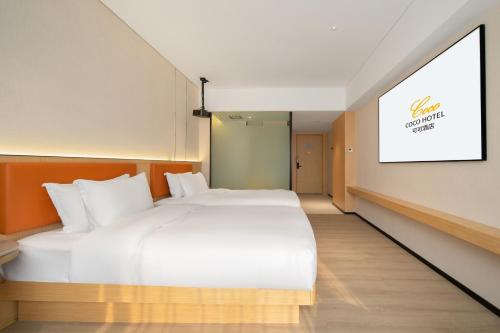 a large white bed in a room with a painting on the wall at 广州白云国际机场可可Coco酒店-广交会期间展馆穿梭巴士 in Huadu