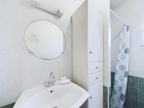 ein weißes Badezimmer mit Waschbecken und Spiegel in der Unterkunft Maison de vacances pour 4, St-Hilaire-de-Riez in Saint-Hilaire-de-Riez